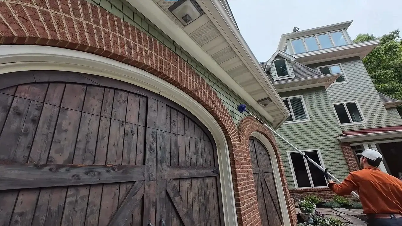 Clearing spider webs and nests from roof eaves above a garage