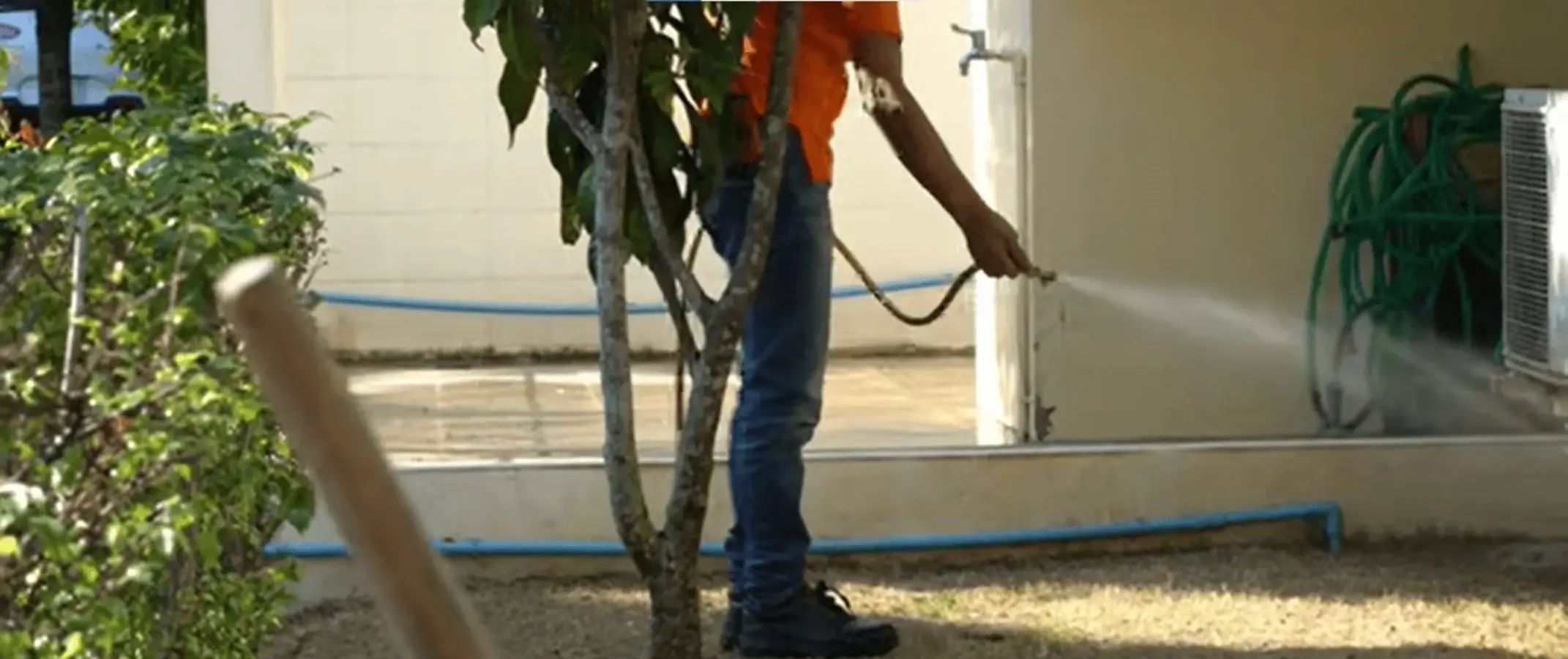 Spraying a pest barrier along the outside wall of a home